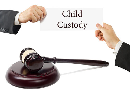 gavel between two hands holding up a sign that reads child custody