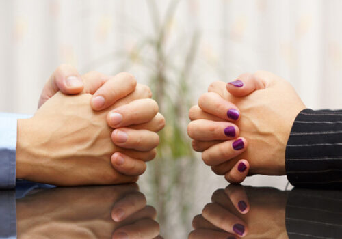 two sets of hands folded on a table in discussion over divorce proceedings in Illinois