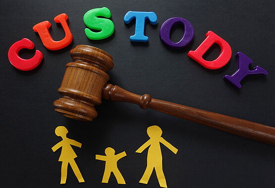 colorful magnets spelling out custody above a gavel and paper cut outs of a family