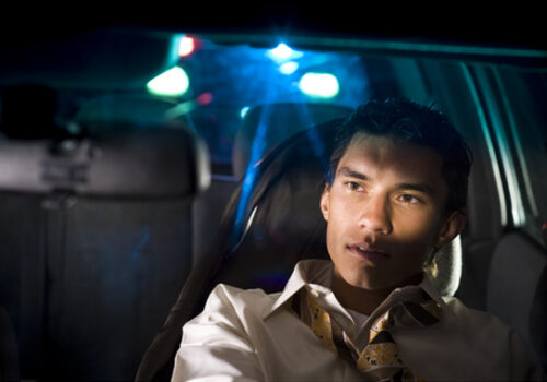 man behind the wheel of a car getting pulled over for a DUI