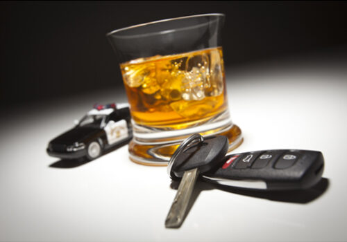 alcoholic beverage sitting next to keys and a toy police car