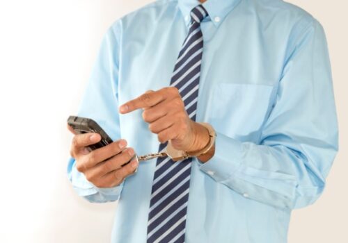 A man in handcuffs getting ready to call a criminal defense attorney in Pekin IL