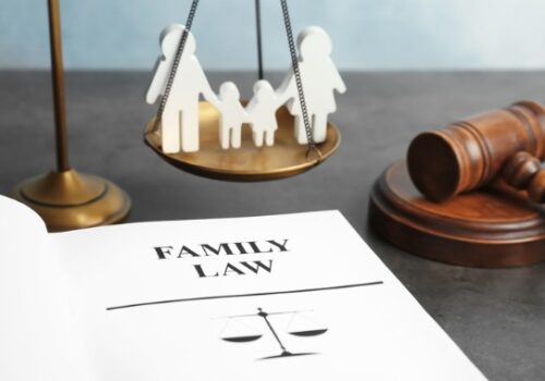 A scale with a wood dolls on it, and a family law book, representing a Peoria IL Family Lawyer
