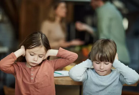 A brother and sister cover their ears as they listen to their parents fight. If you need a lawyer for a Divorce in Pekin IL, Borsberry Law is here to help.